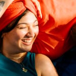 A woman is lying with her head on a man's chest, both smiling at each other